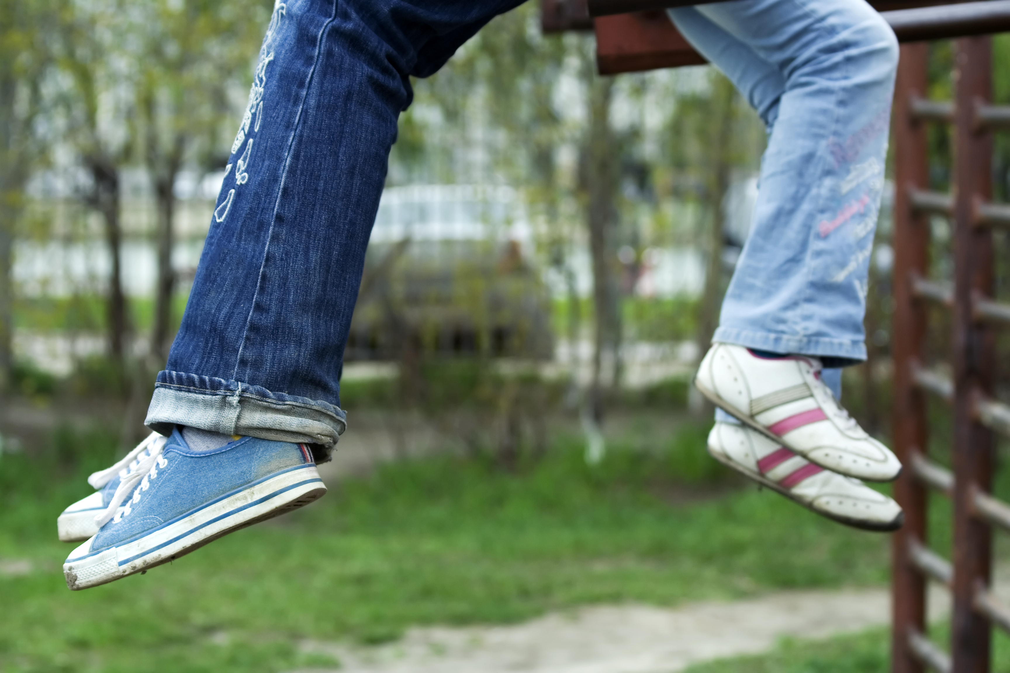 Legs of two young people wearing jeans and trainers.